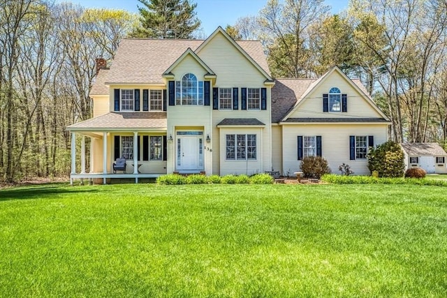 colonial inspired home with a chimney, a front lawn, and a porch