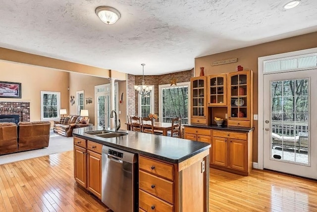 kitchen with a sink, dishwasher, light wood-style flooring, a chandelier, and a textured ceiling