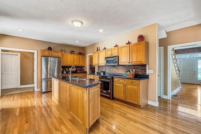 kitchen with stainless steel appliances, a sink, baseboards, dark countertops, and recessed lighting