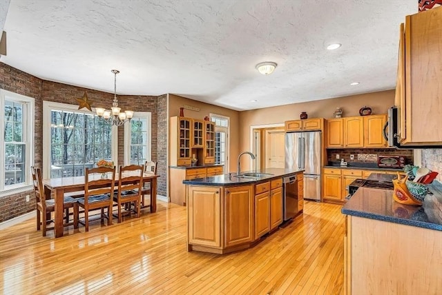 kitchen featuring a sink, stainless steel appliances, a chandelier, light wood-style floors, and decorative backsplash