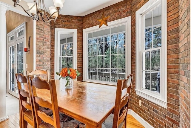 dining room featuring brick wall, a chandelier, and light wood finished floors