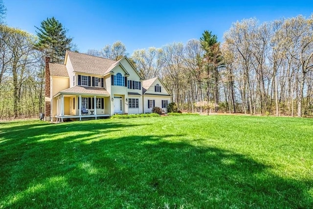 view of front of property featuring a chimney, a front yard, and a shingled roof