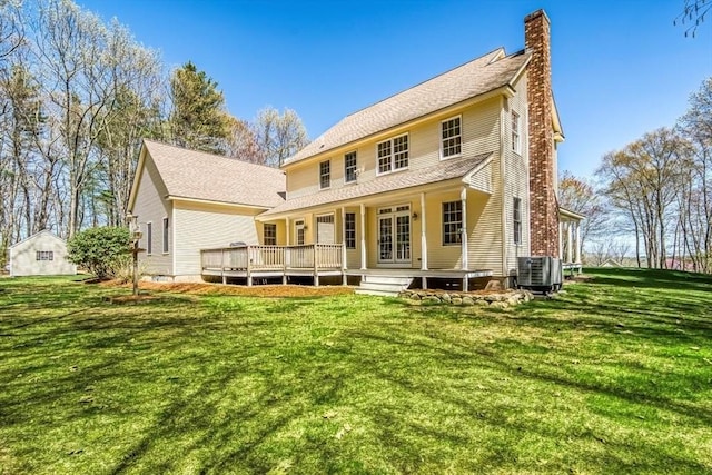 rear view of house with a chimney, a wooden deck, central AC, and a yard