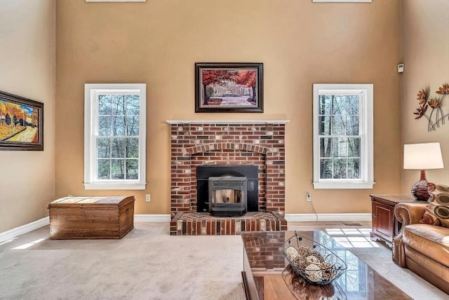 carpeted living area with baseboards, healthy amount of natural light, a wood stove, and a high ceiling