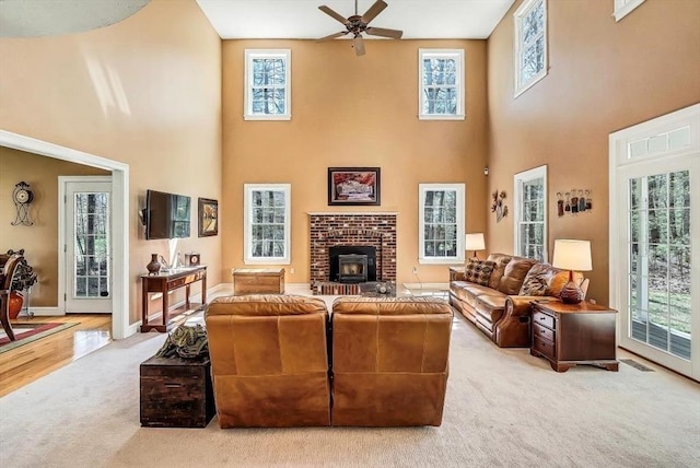 carpeted living room featuring a towering ceiling, plenty of natural light, ceiling fan, and baseboards