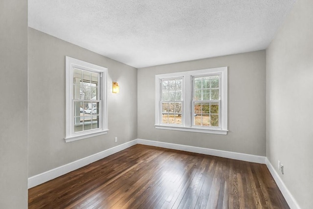 unfurnished room featuring dark wood-type flooring and a textured ceiling