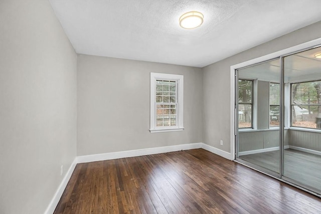 unfurnished room with dark wood-type flooring and a textured ceiling