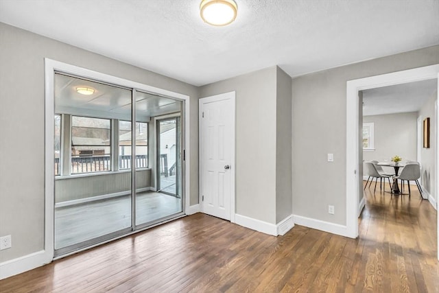 empty room with a textured ceiling and dark hardwood / wood-style floors