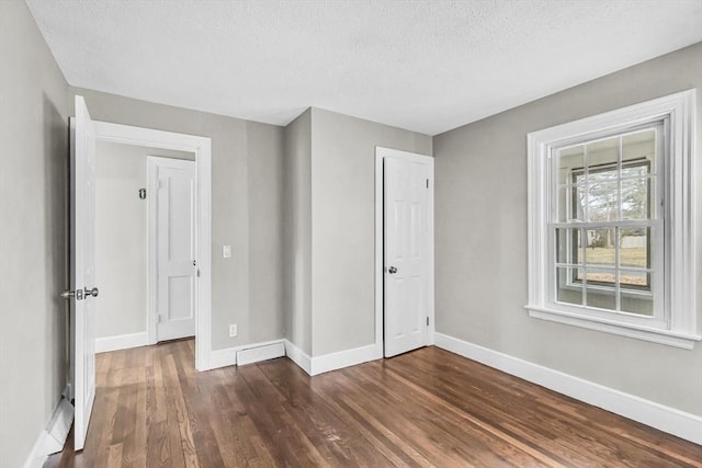 empty room featuring a textured ceiling and dark hardwood / wood-style flooring