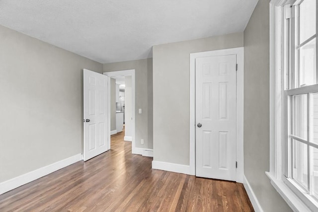 unfurnished bedroom with a closet and dark wood-type flooring