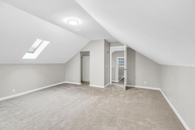 additional living space with vaulted ceiling with skylight and carpet flooring