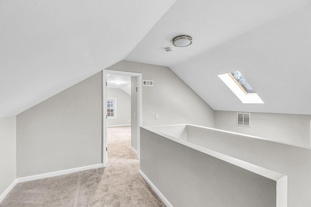 additional living space with light colored carpet and vaulted ceiling with skylight