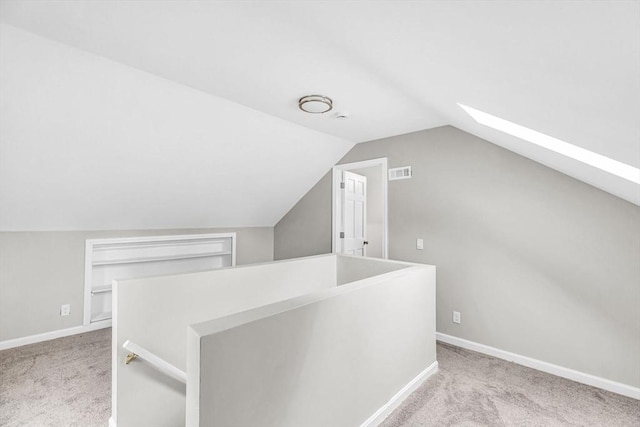 bonus room featuring lofted ceiling with skylight and light colored carpet