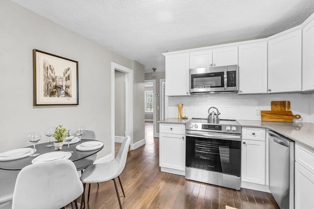 kitchen with dark wood-type flooring, white cabinetry, decorative backsplash, and appliances with stainless steel finishes