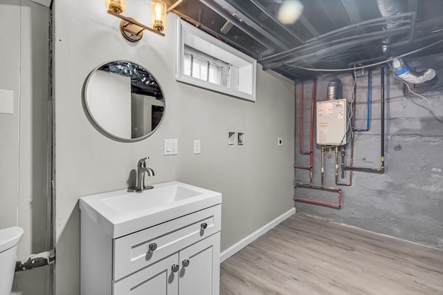 bathroom with vanity, toilet, water heater, and wood-type flooring