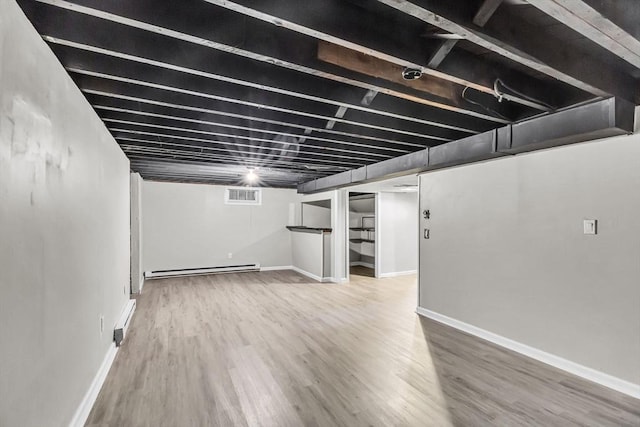 basement with hardwood / wood-style flooring and a baseboard radiator