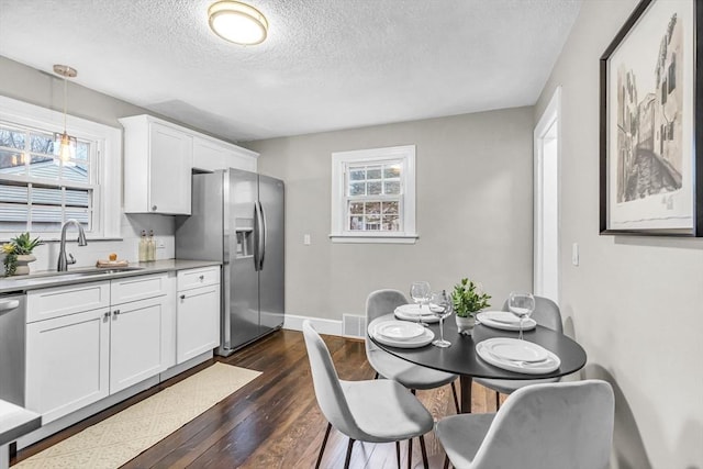 kitchen featuring pendant lighting, sink, white cabinets, a textured ceiling, and stainless steel appliances