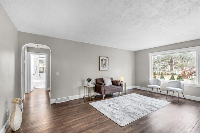 living area with a textured ceiling and dark hardwood / wood-style flooring