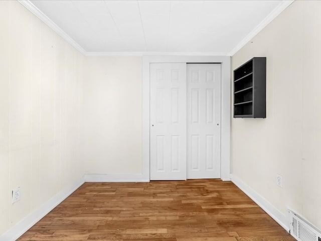 unfurnished bedroom with hardwood / wood-style floors, crown molding, and a closet