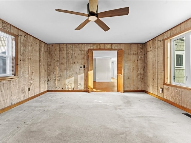 carpeted spare room with ceiling fan and wood walls