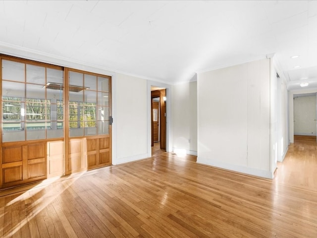 spare room with crown molding and light wood-type flooring