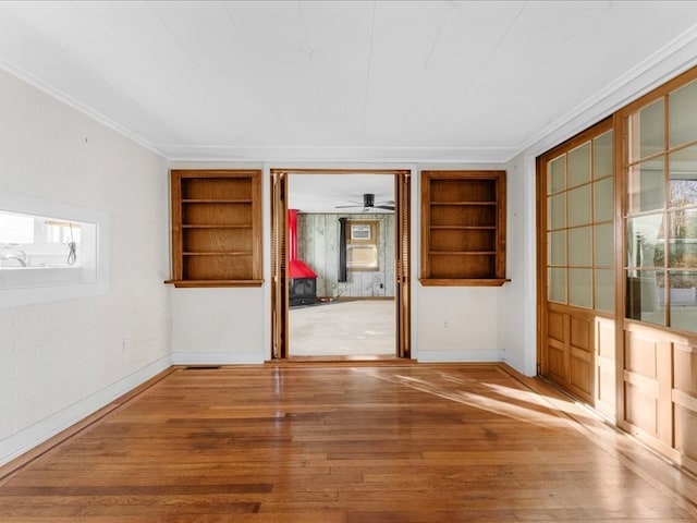 spare room with built in shelves, wood-type flooring, and a wealth of natural light