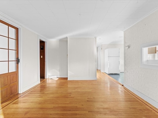 unfurnished room featuring ornamental molding, brick wall, and light wood-type flooring