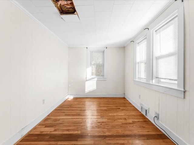 spare room featuring wood-type flooring, crown molding, and wooden walls