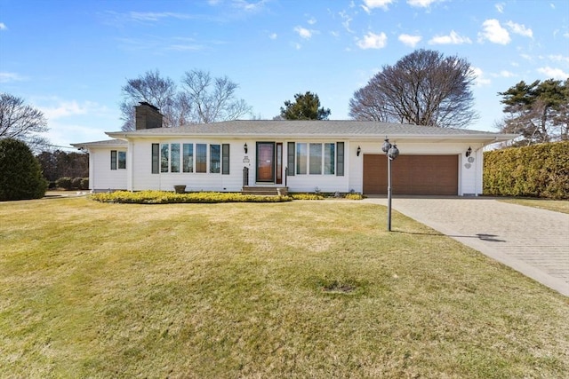 single story home with decorative driveway, a front lawn, a garage, and a chimney