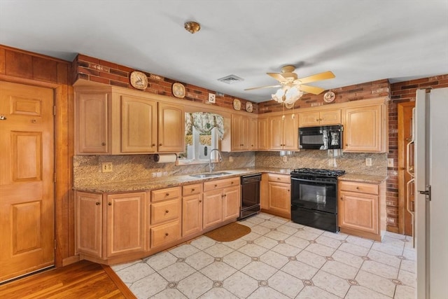 kitchen featuring decorative backsplash, black appliances, visible vents, and a sink