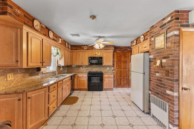 kitchen featuring visible vents, black appliances, a sink, radiator heating unit, and light stone countertops