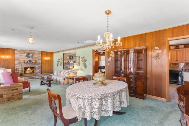 dining space featuring light carpet, wood walls, and a fireplace