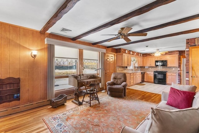 living area featuring beam ceiling, visible vents, light wood finished floors, and wood walls