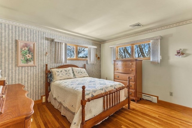 bedroom featuring visible vents, light wood-style floors, wallpapered walls, baseboards, and baseboard heating