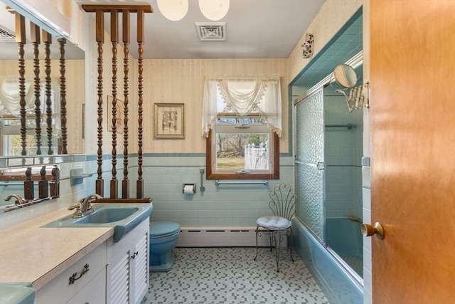 full bathroom with a baseboard heating unit, a wainscoted wall, toilet, vanity, and tile walls