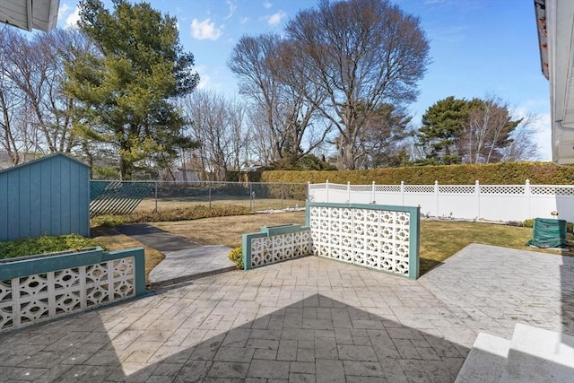 view of patio featuring an outbuilding, a storage unit, and a fenced backyard