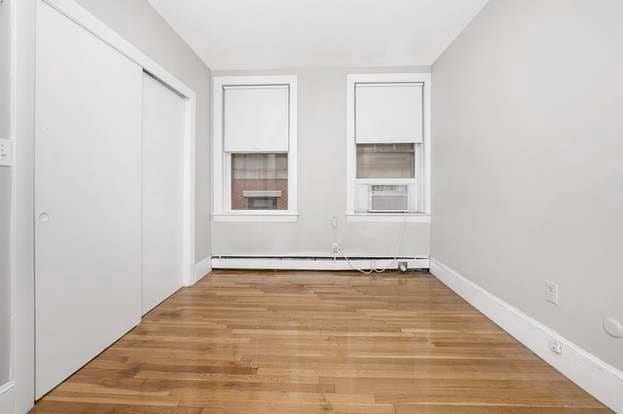 unfurnished bedroom with cooling unit, baseboard heating, and light wood-type flooring