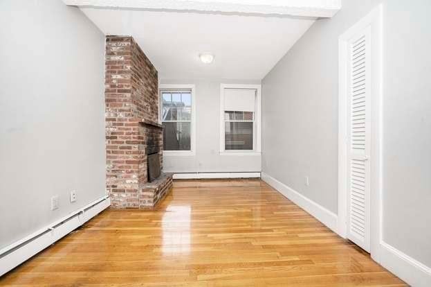 unfurnished living room featuring light wood-type flooring, a brick fireplace, vaulted ceiling with beams, and baseboard heating