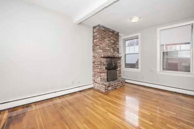 unfurnished living room with a fireplace, hardwood / wood-style floors, beam ceiling, and a baseboard radiator