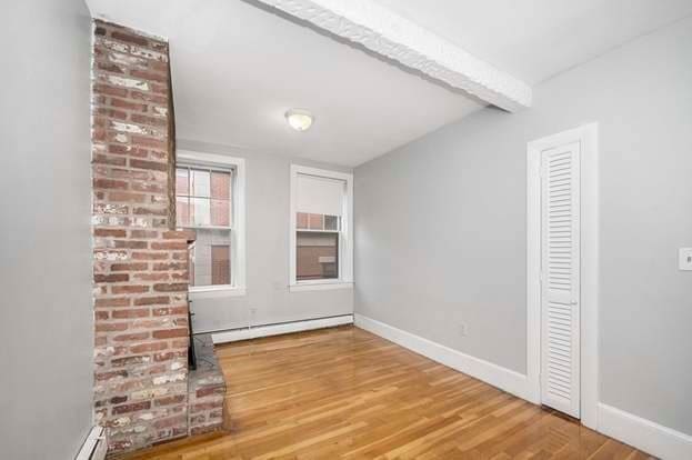 unfurnished living room with beamed ceiling, a baseboard radiator, and wood-type flooring