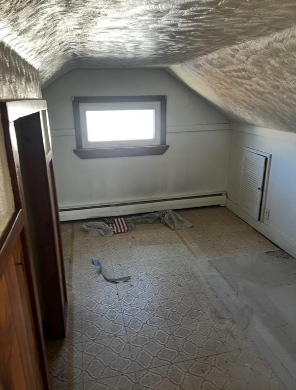 bonus room featuring a baseboard heating unit and vaulted ceiling