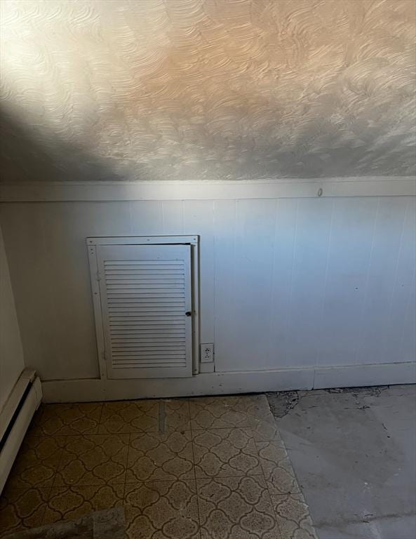 bonus room with a textured ceiling and a baseboard heating unit