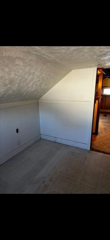 bonus room featuring lofted ceiling and a textured ceiling