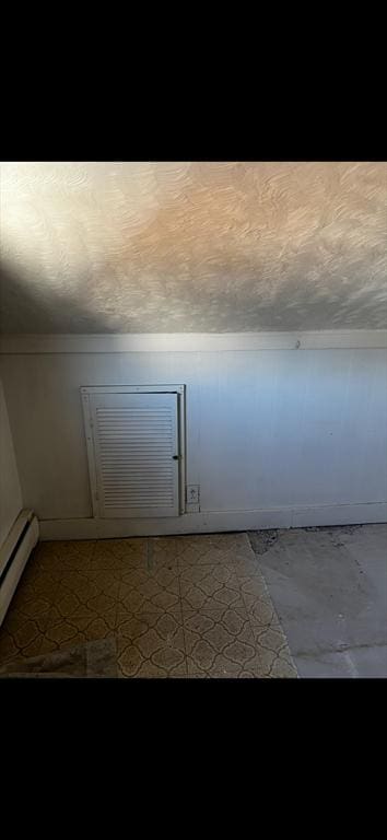 bonus room with a textured ceiling and a baseboard heating unit