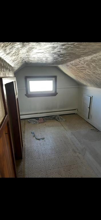 additional living space with a baseboard radiator and lofted ceiling