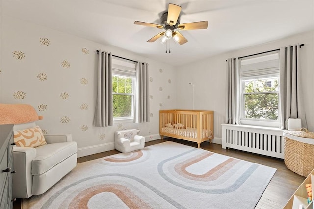 61 Howitt Rd, Boston, MA 02132 - bedroom with radiator heating unit, wood finished floors, baseboards, a nursery area, and ceiling fan