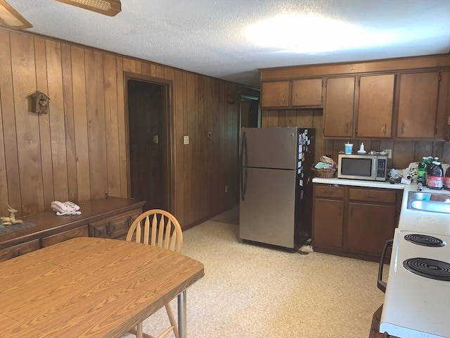389 Breakneck Rd, Southbridge, MA 01550 - kitchen with stainless steel appliances, light countertops, wooden walls, ceiling fan, and a textured ceiling
