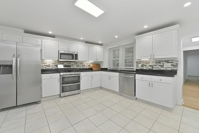 kitchen featuring backsplash, white cabinetry, light tile patterned flooring, and stainless steel appliances