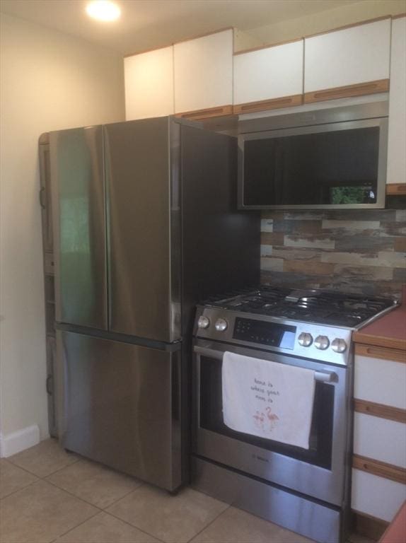 22 Smith St, Norton, MA 02766 - kitchen featuring stainless steel appliances, tasteful backsplash, white cabinetry, light tile patterned floors, and dark countertops