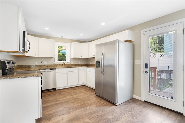 kitchen with appliances with stainless steel finishes, light hardwood / wood-style flooring, a healthy amount of sunlight, and white cabinetry